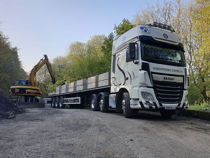 Articulated flatbed lorry loaded with concrete blocks for site delivery
