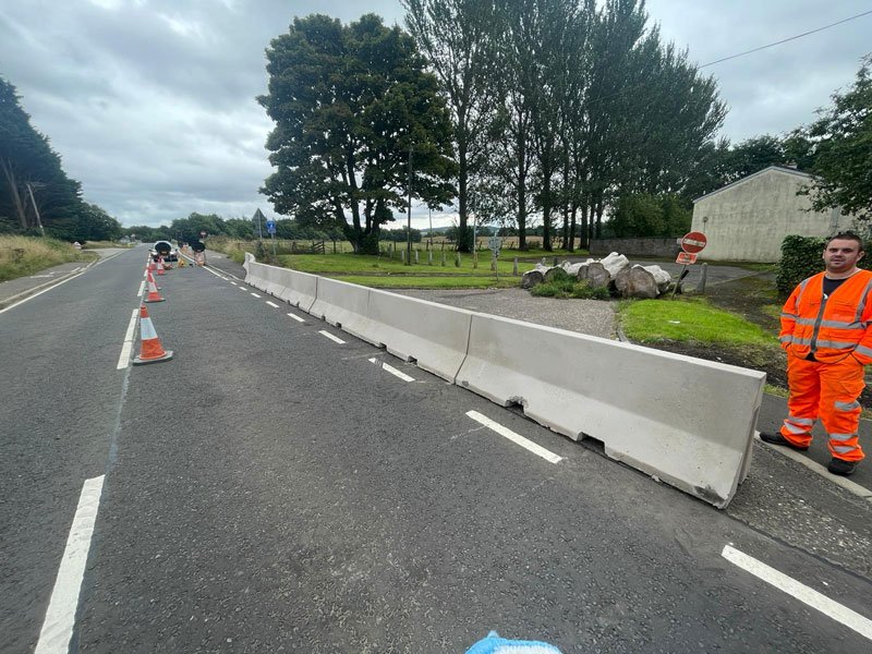 Jersey barriers separating a live carriageway with a worker in hi-vis alongside
