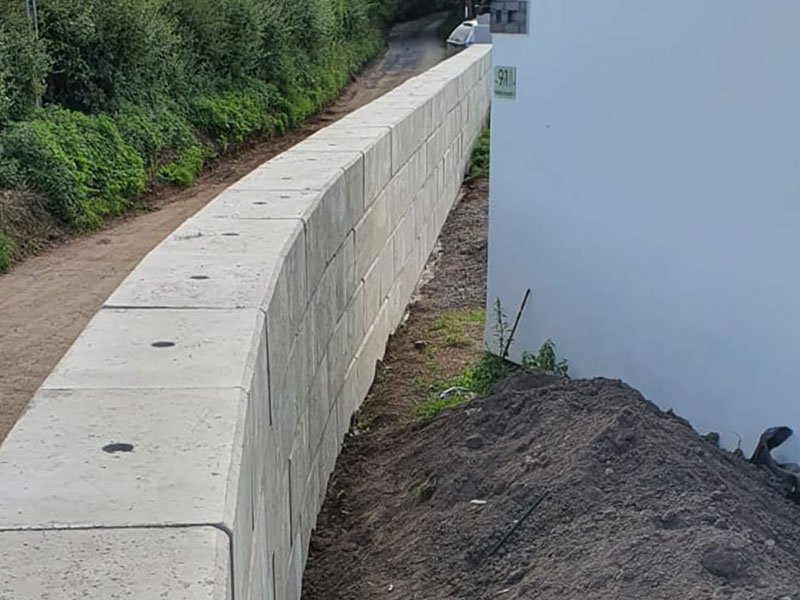 Curved Duo block wall forming a flood defence barrier alongside a footpath