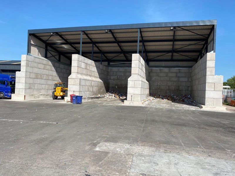 Interlocking block bay divisions beneath an open-fronted steel storage canopy
