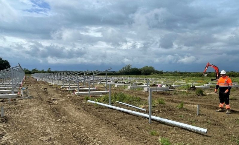 Long rows of solar mounting frames being erected on a ballasted field