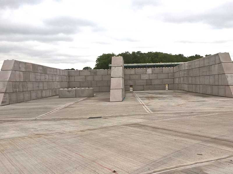 Legato block walls forming open vehicle bays on a large concrete yard
