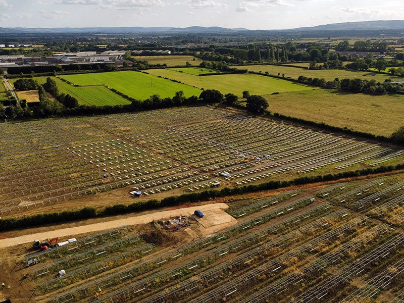 Aerial view of rows of ground-mounted solar frames across farmland