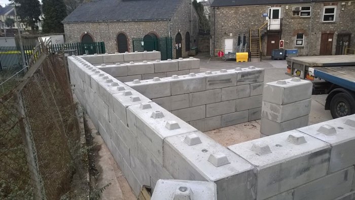 Duo interlocking blocks forming divided storage bays in a walled yard