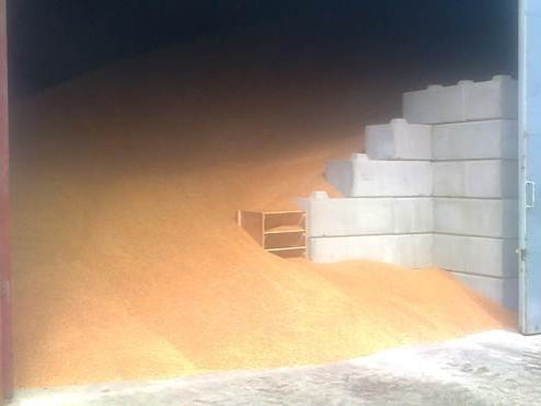 Grain heaped against a stepped interlocking block wall inside a store