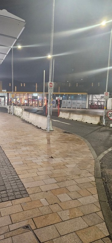 Jersey barriers lining a paved walkway outside a terminal at night