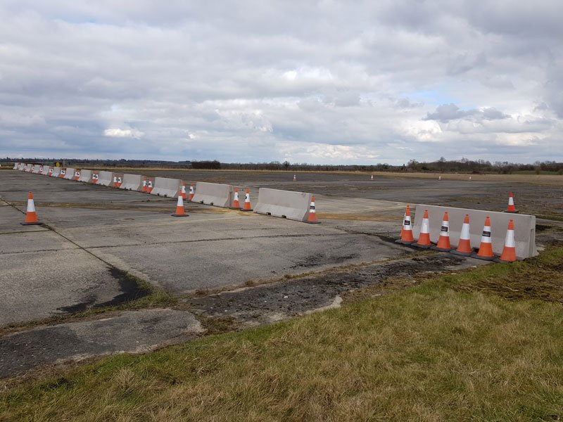 Jersey barriers and traffic cones closing off an open airfield apron