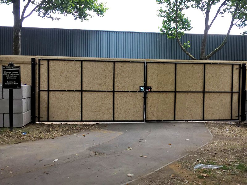 Timber-faced hoarding gate ballasted by concrete kentledge blocks at a site entrance