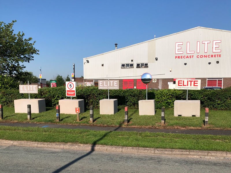 Row of non-drill concrete post-holder blocks supporting signage outside a factory