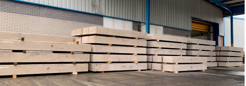 Solar ballast blocks stacked on timber pallets inside a storage building