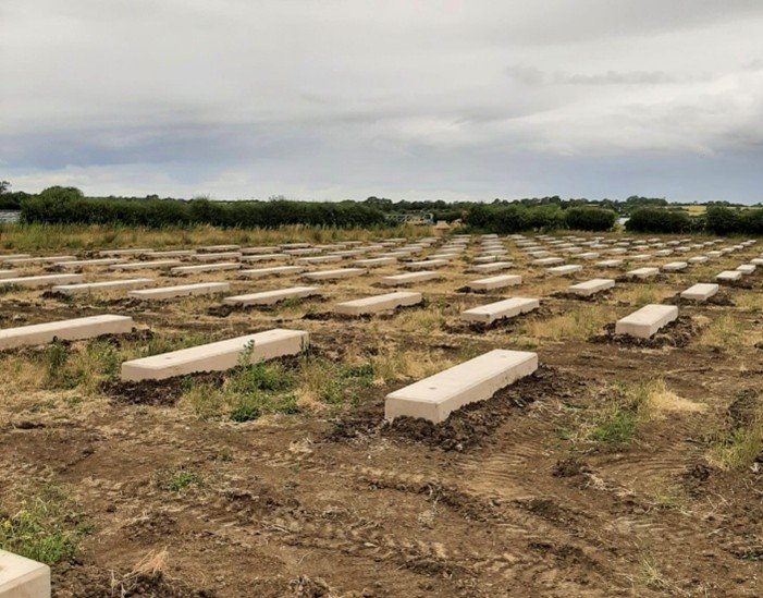 Rows of solar ballast blocks laid out across a prepared field