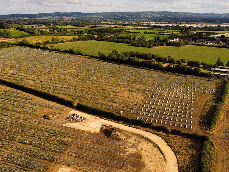 Aerial view of a solar farm under construction across open farmland