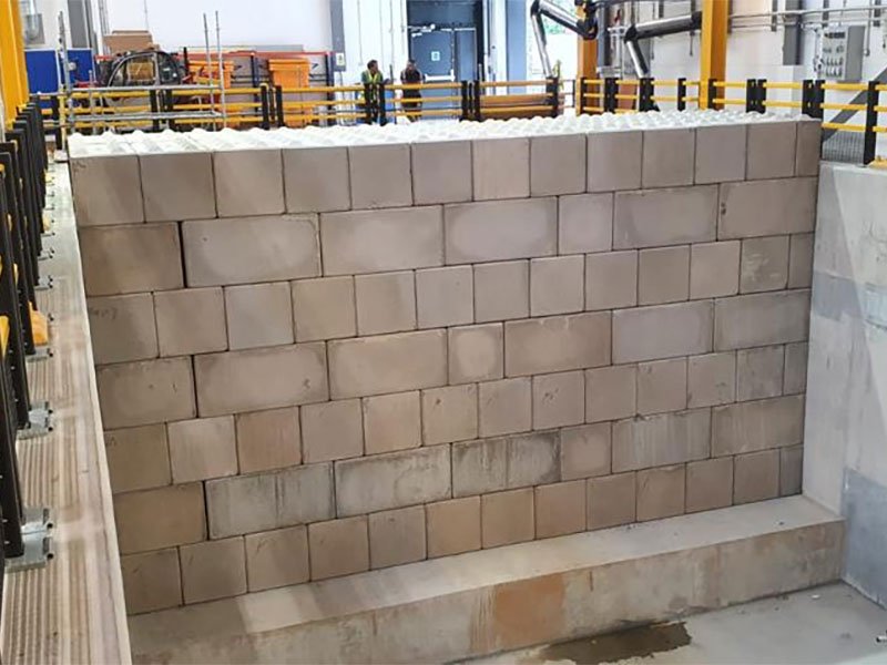 Tall interlocking block bunker wall inside an industrial plant with edge railings