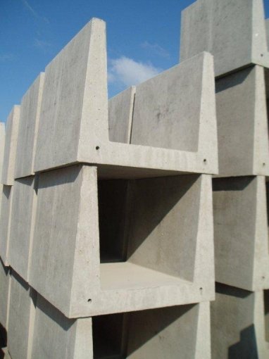 Large precast concrete troughs stacked on end in a storage yard
