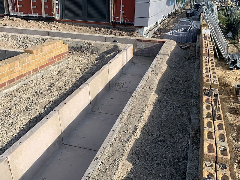 Precast concrete channel run installed in a trench beside a building