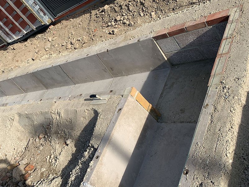 Large precast channel section installed in an excavation beside a building