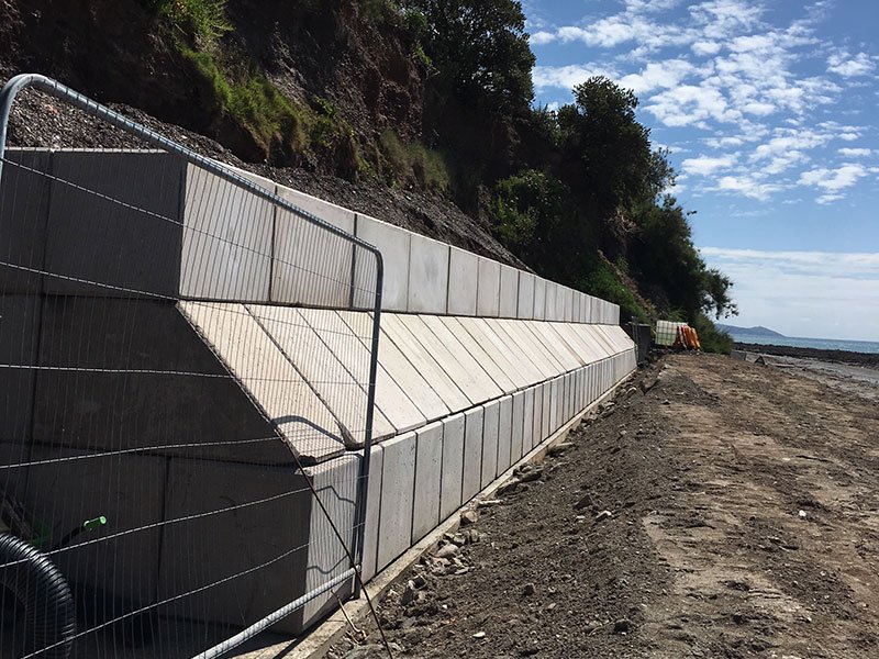 Interlocking block sea defence wall running along an eroding coastal cliff