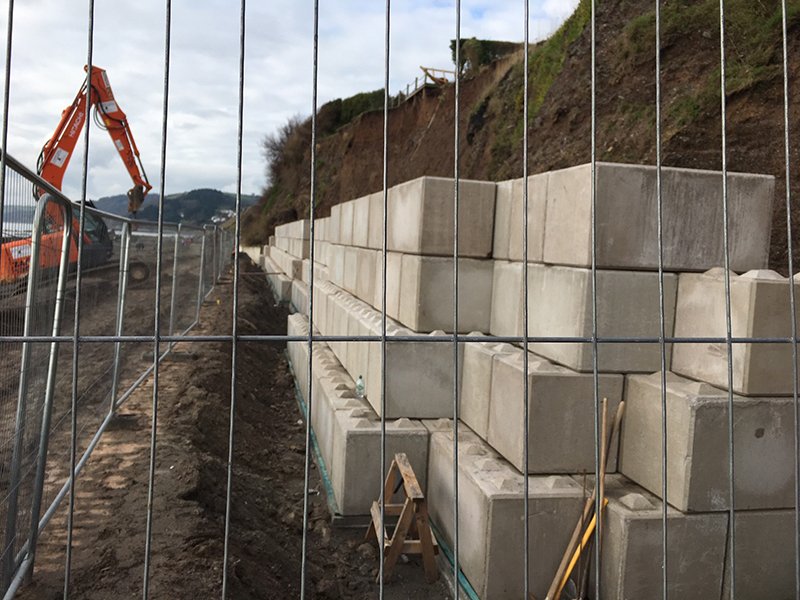 Legato blocks stacked against an eroding slope behind temporary fencing