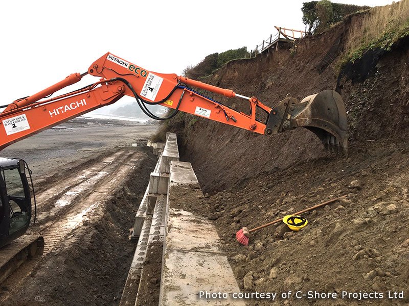Excavator working behind a Legato block wall below a slipped cliff