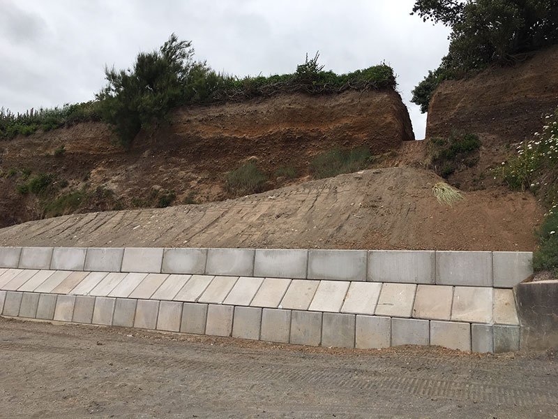 Stepped courses of interlocking blocks retaining a slumped coastal cliff face