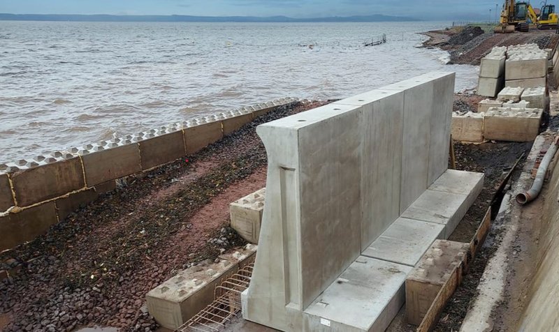 Large precast wall unit being installed as sea defence on a shingle shore
