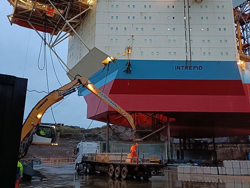 Rig hull above counterweight blocks stacked on a decommissioning quayside