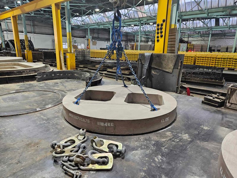 Circular bespoke cover slab with two openings lifted on chains in the works