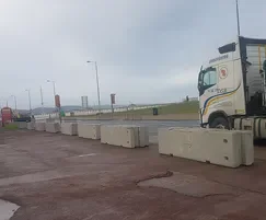 Temporary concrete barriers spaced across a promenade with a delivery lorry behind