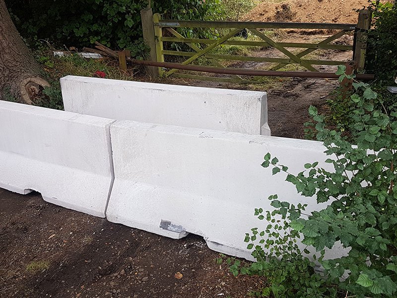 White Jersey barriers blocking a track beside a timber farm gate