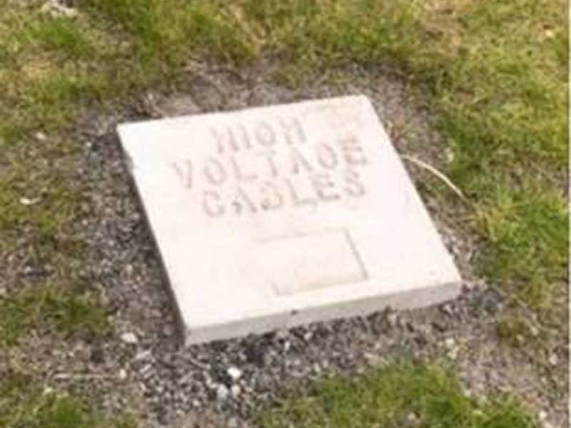 High voltage cable marker block set flush into grass at ground level