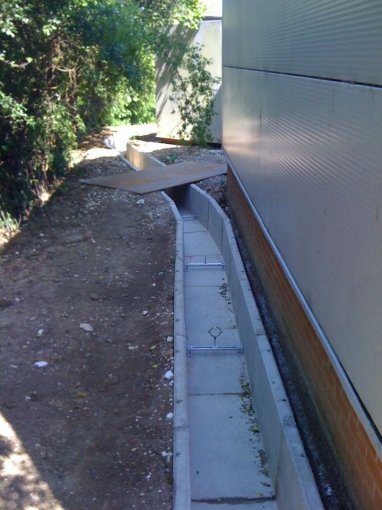Precast concrete channel installed along the base of a building wall