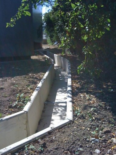 Precast concrete cable troughs laid in a line through overgrown ground