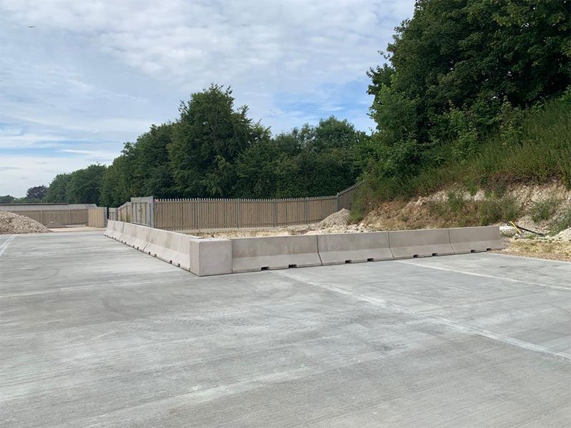 Run of Jersey barriers segregating a concrete hardstanding from a grassed bank