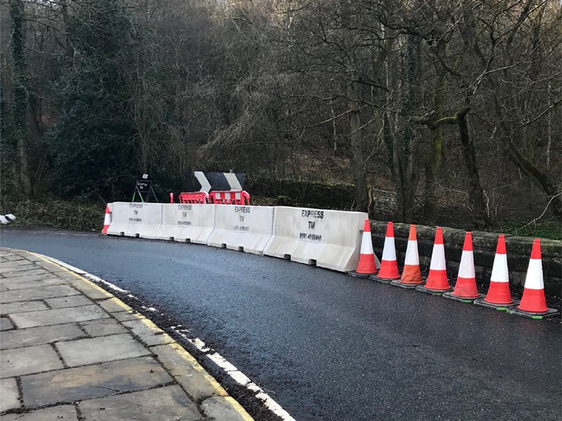 Jersey barriers and traffic cones shielding a newly resurfaced road edge