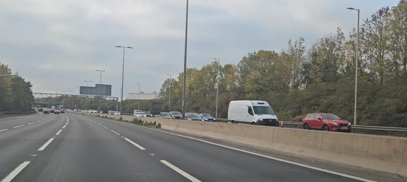 Traffic flowing along a tree-lined dual carriageway