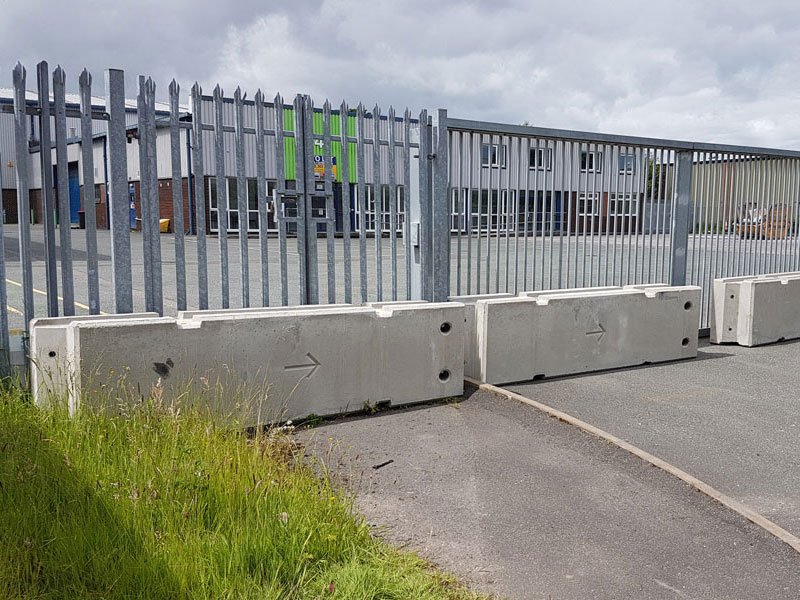 Concrete barriers set in front of a palisade fence at industrial premises
