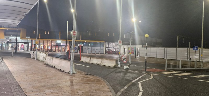 Concrete barriers lining a station forecourt lit by street lighting at night