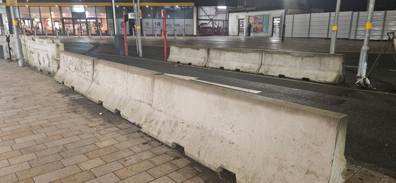 Jersey barriers lining a pedestrian walkway at a station bus interchange