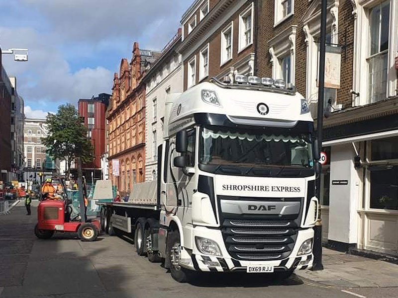 Flatbed delivery lorry unloading with a forklift on a city street