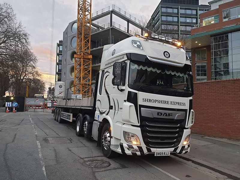 Flatbed lorry loaded with precast concrete units at a city construction site