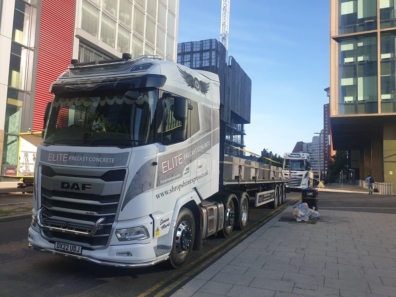 Delivery lorry with a flatbed trailer parked on a city-centre street