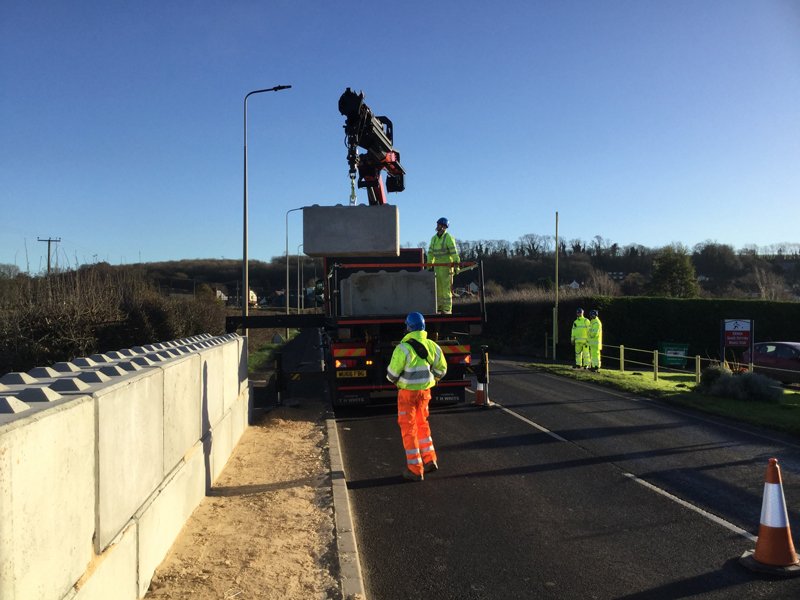 Lorry crane offloading Legato blocks on a road beside a new block wall