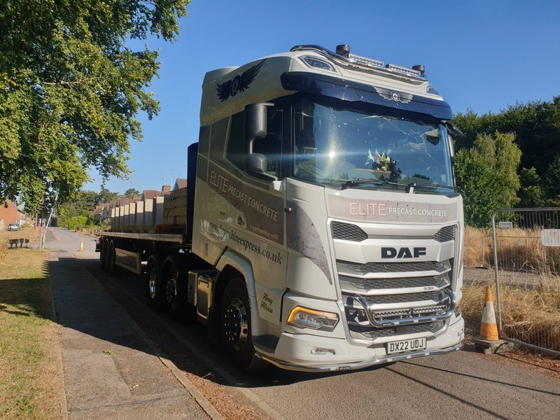 Flatbed delivery lorry carrying precast concrete units into a housing development