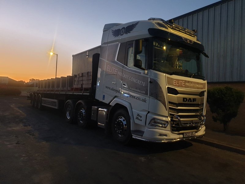 Loaded delivery lorry leaving an industrial yard at dusk