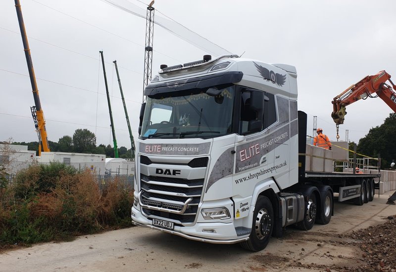 Articulated flatbed delivery lorry fitted with side rail fall protection on site