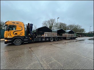 Crane-equipped delivery lorry loaded with precast units on a yard
