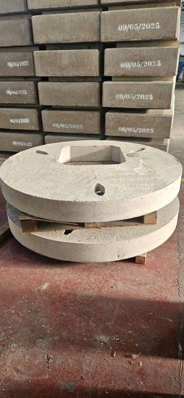 Circular 1500 cover slabs stacked beside date-stamped units in the factory