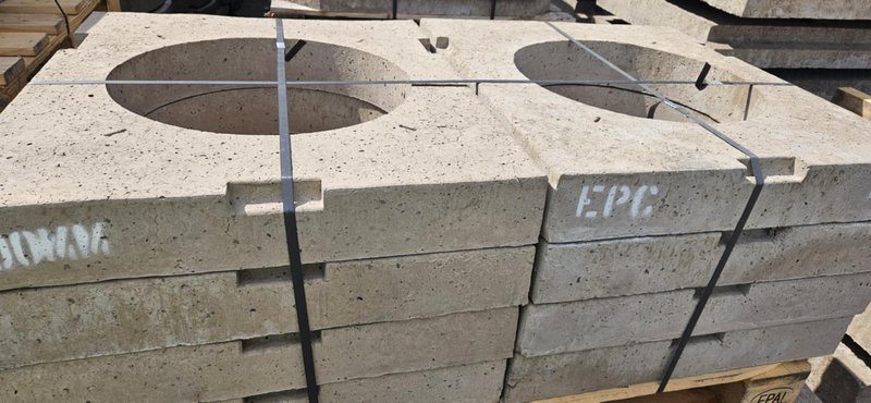 Stacked precast gully cover slabs with circular openings in a yard