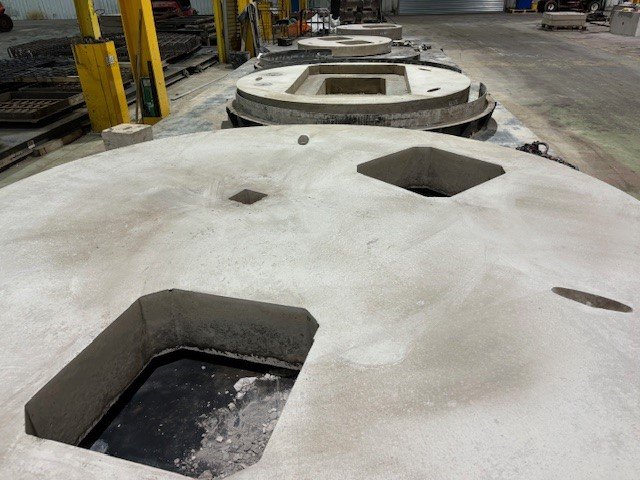 Large circular cover slab with several square and round access openings in the works