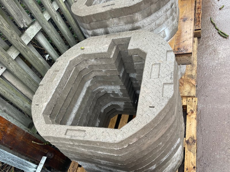 Notched precast manhole seating ring stacked on timber bearers
